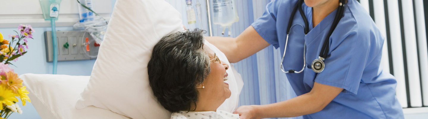 Nurse adjusting patient's pillow on hospital bed