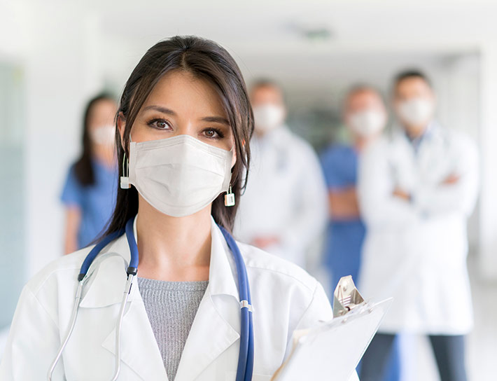 Female doctor wearing mask, doctors in background